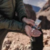 Hiker applying Lifesystems Mountain Sun Cream SPF 50+ during a mountain adventure